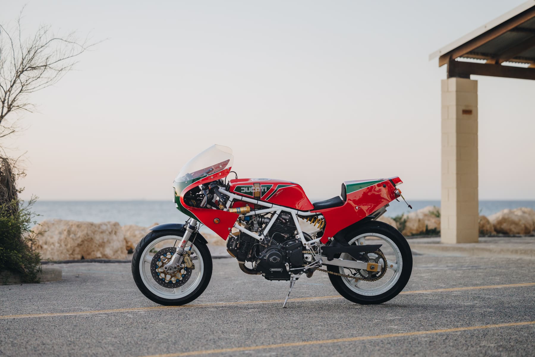 Photo de profil latérale d'une moto Ducati personnalisée garée à la plage