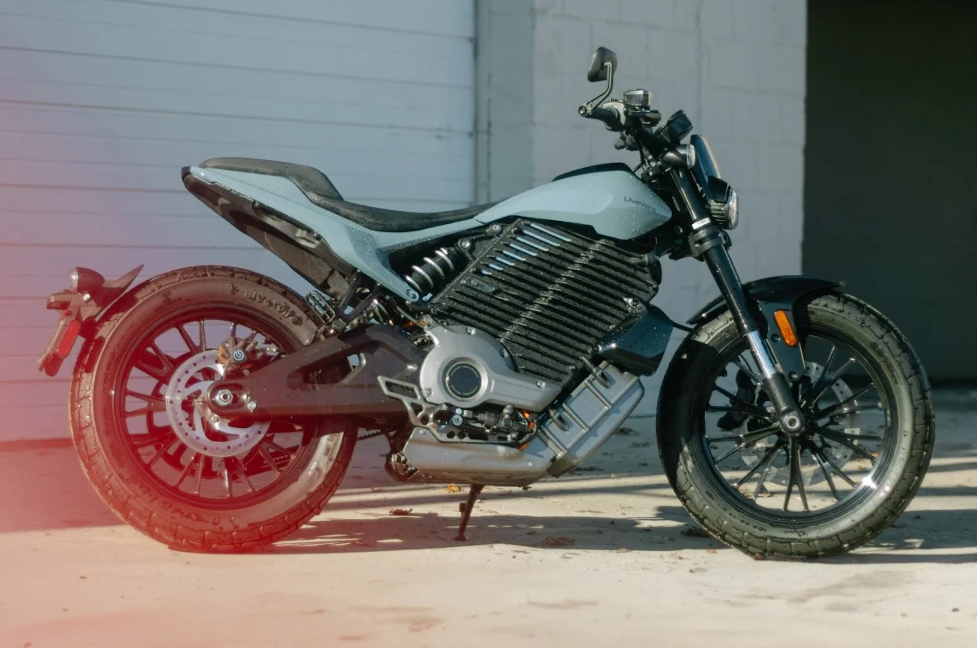 Une moto électrique devant un garage.